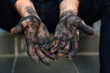Kirli işçiler merdivenlerde oturuyor, elleri kapalı.