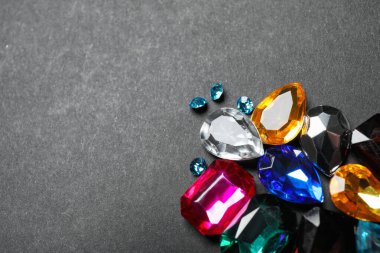 Pile of different beautiful gemstones on black background. Space for text clipart