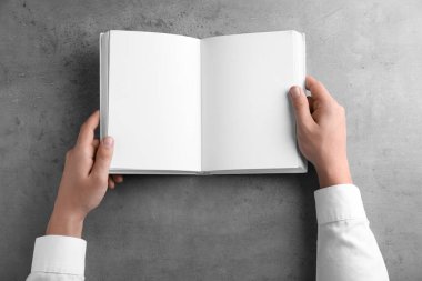 Gri masada boş bir kitap tutan adam, üst manzara. Tasarım için hazırlan