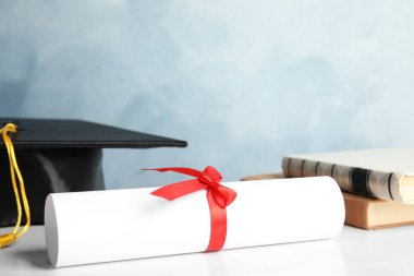 Açık mavi arka planda beyaz ahşap masa üzerine öğrenci diploması