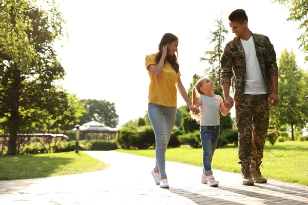 Чоловік у військовій формі та його сім'я гуляють у сонячному парку — стокове фото