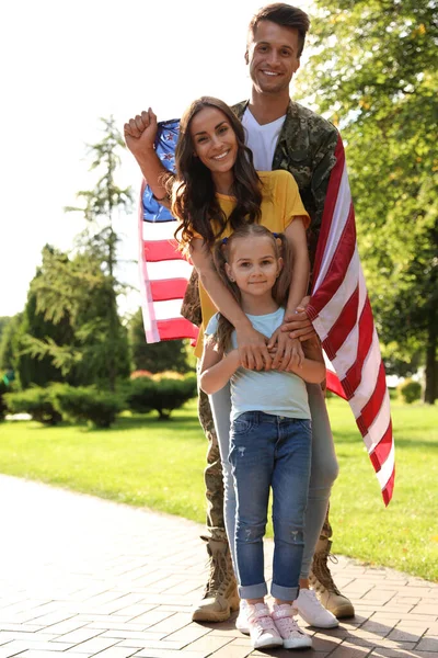Hombre en uniforme militar con bandera americana y su familia en Sunny Park — Foto de Stock
