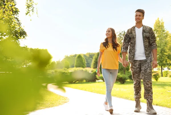 身穿军服的男人和他的女朋友在阳光灿烂的公园散步 — 图库照片