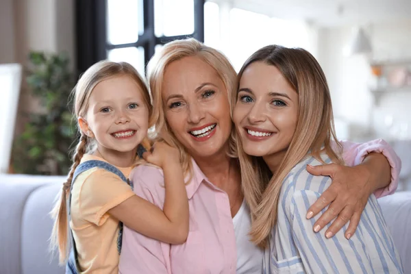 Jonge vrouw met volwassen moeder en kleine dochter in de woonkamer — Stockfoto