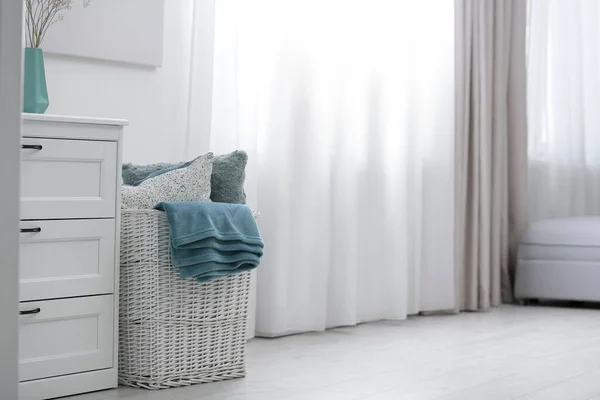 Cesta con cuadros suaves y almohadas en la habitación. Espacio para texto — Foto de Stock