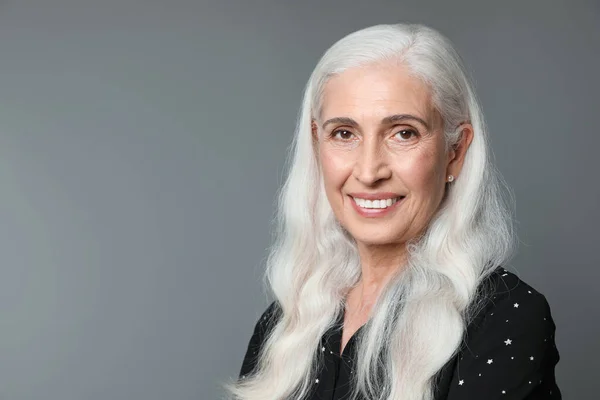 Porträtt av vacker mogen kvinna på grå bakgrund, utrymme för text — Stockfoto