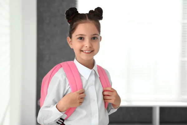Ragazza felice in uniforme scolastica con zaino al chiuso — Foto Stock