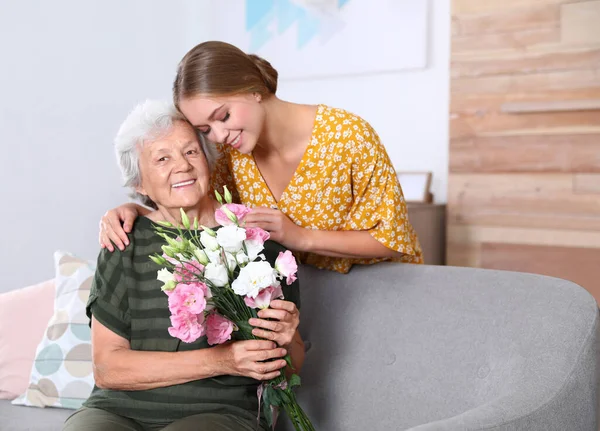 Mujer joven felicitando a su madre mayor en casa. Feliz Día de la Madre —  Fotos de Stock