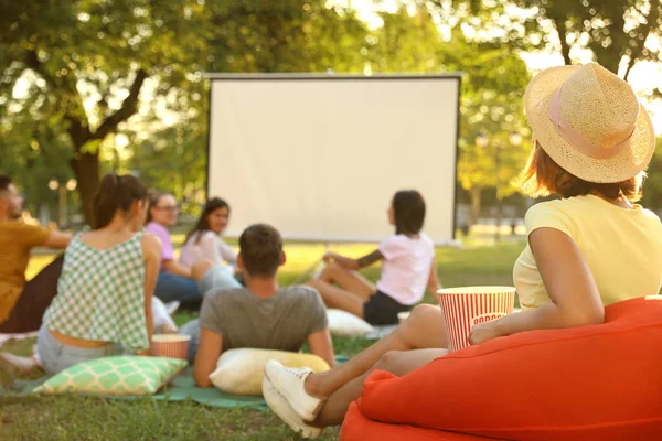 Młodzi ludzie z popcorn oglądania filmu w kinie na otwartym powietrzu. Miejsce na tekst — Zdjęcie stockowe