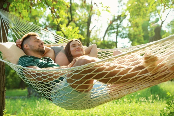 Giovane coppia che riposa in comoda amaca nel giardino verde — Foto Stock