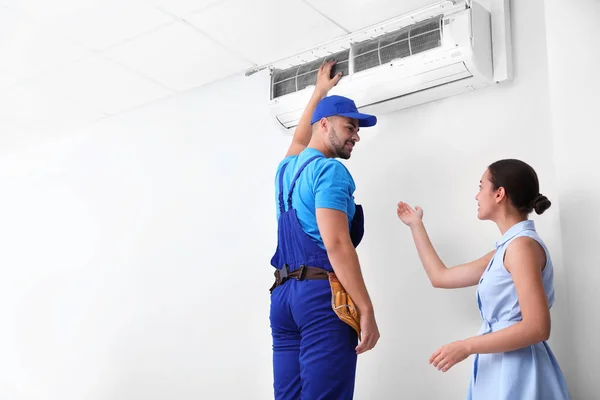 Técnico profissional falando com a mulher sobre ar condicionado dentro de casa. Espaço para texto — Fotografia de Stock