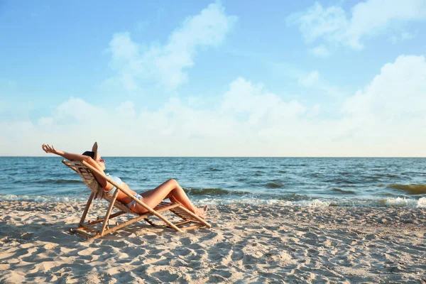 Jeune femme se détendre dans une chaise longue sur la plage — Photo