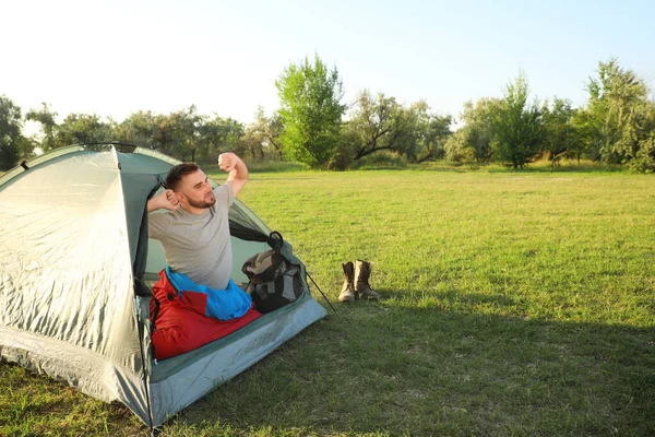 Giovane in sacco a pelo che si estende all'interno tenda da campeggio — Foto Stock