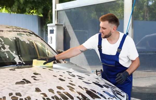 Mladý pracovník čištění automobil s houbou na mytí aut — Stock fotografie