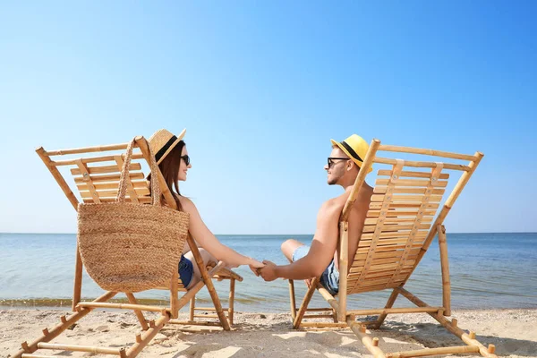 젊은 부부는 해변에서 갑판 의자에서 휴식 — 스톡 사진