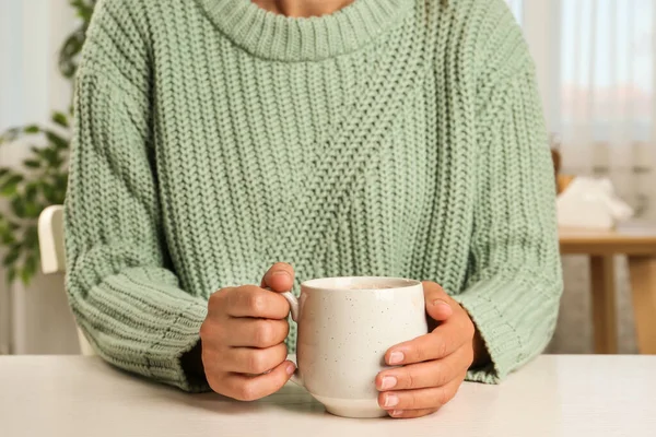 Donna che tiene in mano una tazza di deliziosa bevanda al cacao a tavola bianca, primo piano — Foto Stock