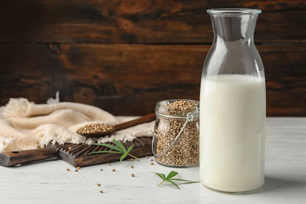 Composition with bottle of hemp milk on white wooden table. Space for text