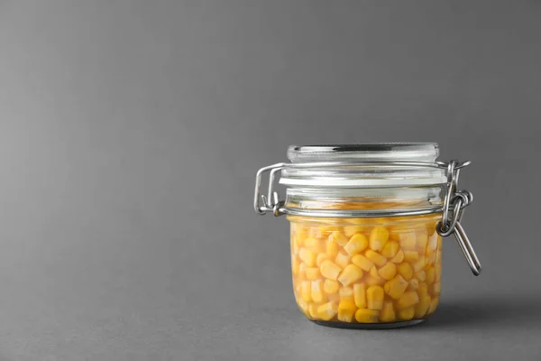 Jar of pickled sweet corn on grey background. Space for text — Stock Photo, Image