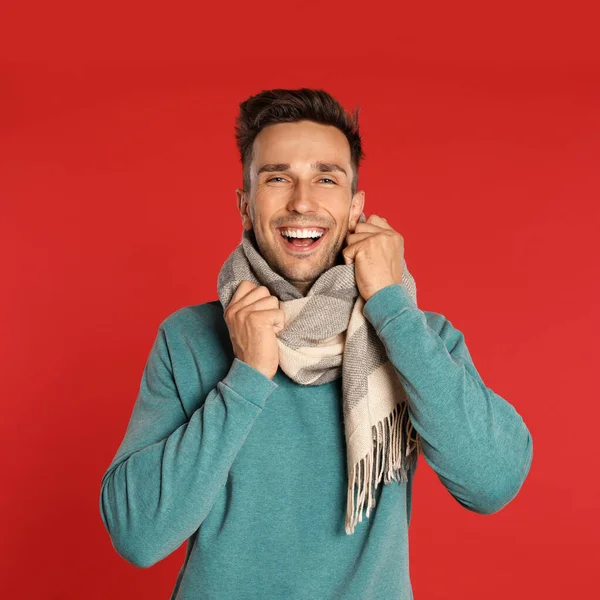 빨간 배경에 스카프 와 스웨트 셔츠를 입은 행복 한 청년. 겨울 계절 — 스톡 사진