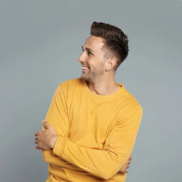 Happy young man in yellow sweatshirt on grey background. Winter season — Stock Photo, Image
