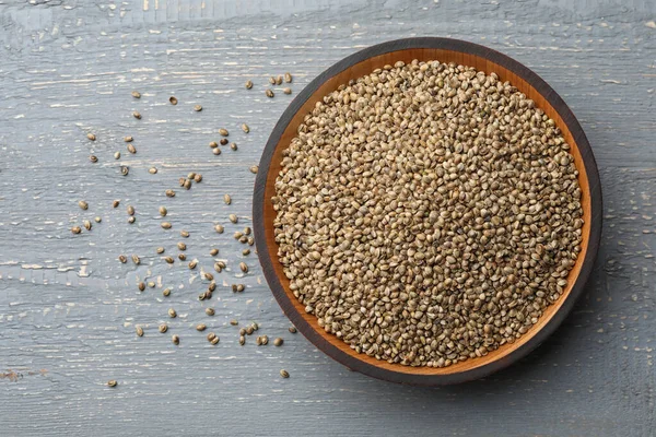 Organic hemp seeds on grey wooden table, top view. Space for text — Stock Photo, Image
