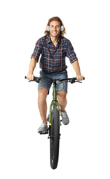 Joven feliz con auriculares montando bicicleta sobre fondo blanco — Foto de Stock
