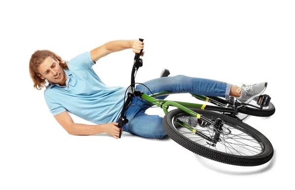 Junger Mann stürzt vor weißem Hintergrund vom Fahrrad — Stockfoto