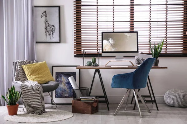 Cómodo lugar de trabajo cerca de la ventana con persianas horizontales en la habitación — Foto de Stock