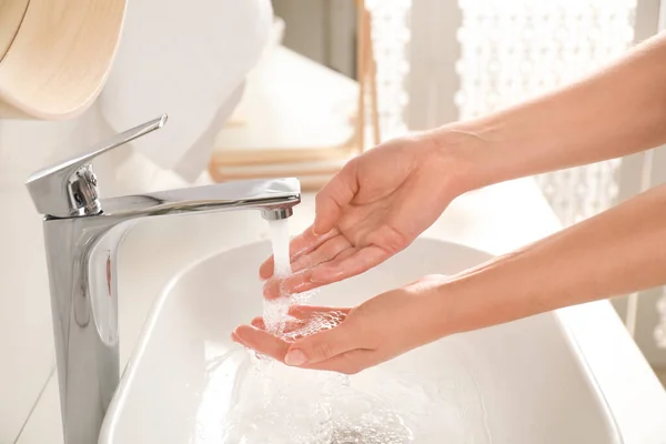 Ung kvinna tvätta händerna över sjunka i badrum, närbild — Stockfoto
