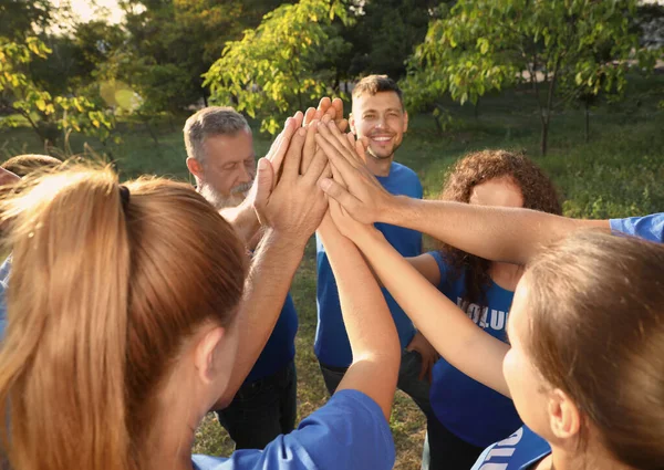 Grupp frivilliga gå med händerna tillsammans utomhus på soliga dagen — Stockfoto