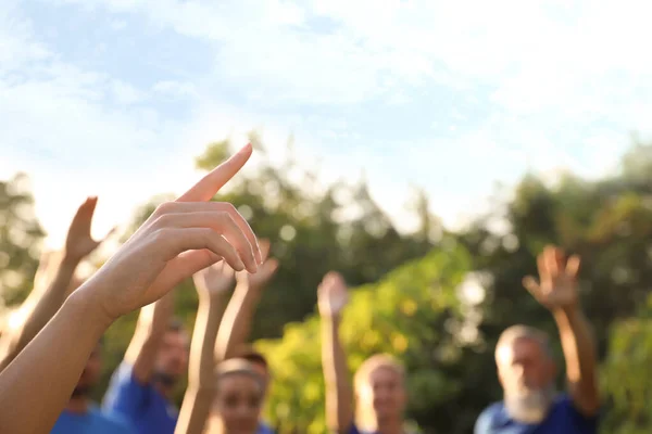 Vrouw bij vrijwilligers bijeenkomst, focus op de hand. Groep mensen buiten — Stockfoto