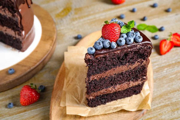 Stück leckerer Schokoladenkuchen mit frischen Beeren auf Holztisch dekoriert — Stockfoto