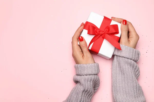 Fiatal nő kezében karácsonyi ajándék rózsaszín háttér, felső nézet. A szöveg helye — Stock Fotó
