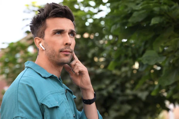 Jeune homme avec écouteurs sans fil dans le parc — Photo