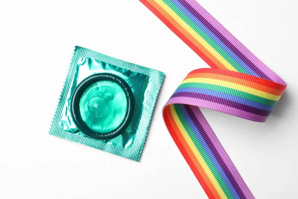 Condón verde y cinta de arco iris sobre fondo blanco, vista superior. Concepto LGBT —  Fotos de Stock