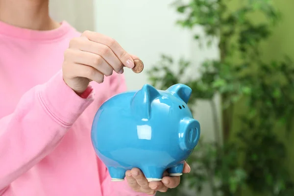 Vrouw zetten munt in spaarvarken bank binnen, close-up — Stockfoto