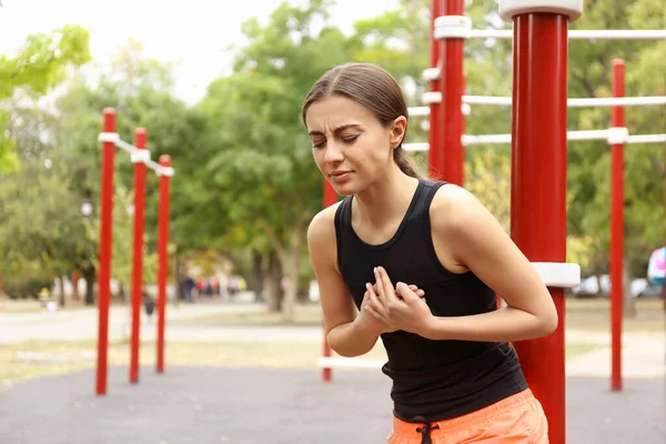 Young woman having heart attack on sports ground