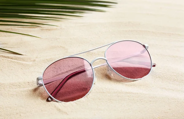 Şık güneş gözlükleri ve beyaz kumdaki tropikal yapraklar. Tatil zamanı. — Stok fotoğraf