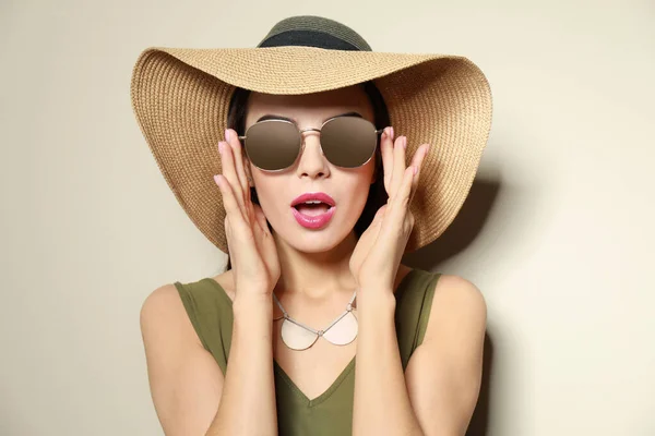 Emotional woman in stylish sunglasses and hat on beige background — Stock Photo, Image