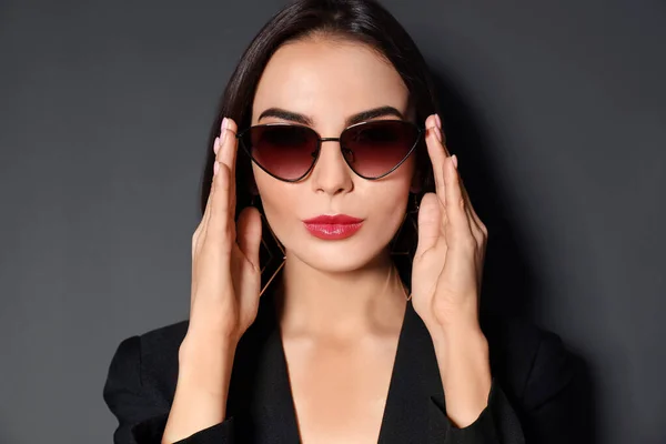 Hermosa mujer con chaqueta y gafas de sol sobre fondo negro — Foto de Stock