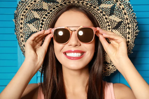 Hermosa mujer con gafas de sol y sombrero cerca de la pantalla plegable de madera azul — Foto de Stock
