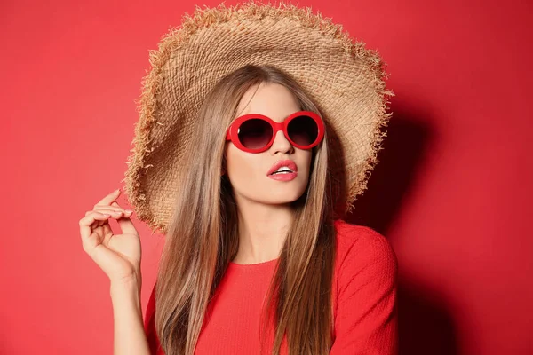 멋진 선글라스를 쓰고 빨간 배경에 모자를 쓴 젊은 여자 — 스톡 사진