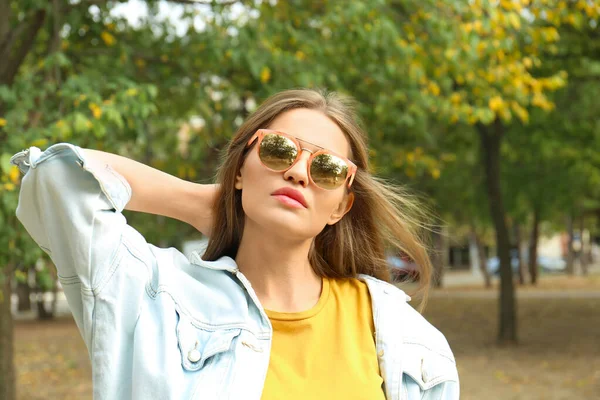 Jovem mulher usando óculos de sol elegantes no parque — Fotografia de Stock