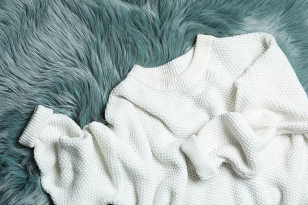 White knitted sweater on green fur rug, flat lay — Stock Photo, Image
