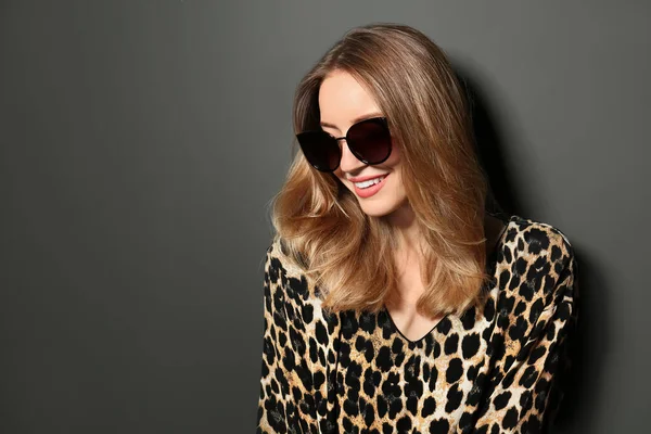 Egy fiatal nő elegáns napszemüveget visel sötét szürke háttérrel. A szöveg helye — Stock Fotó