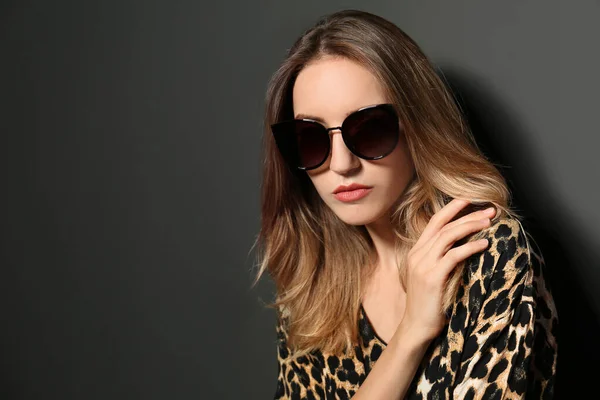 Młoda kobieta w stylowych okularach przeciwsłonecznych na ciemnoszarym tle. Miejsce na tekst — Zdjęcie stockowe
