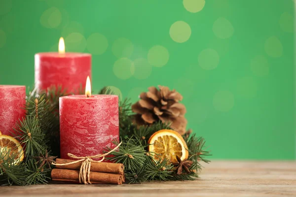 Bela composição de Natal com velas em chamas na mesa contra fundo verde. Espaço para texto — Fotografia de Stock