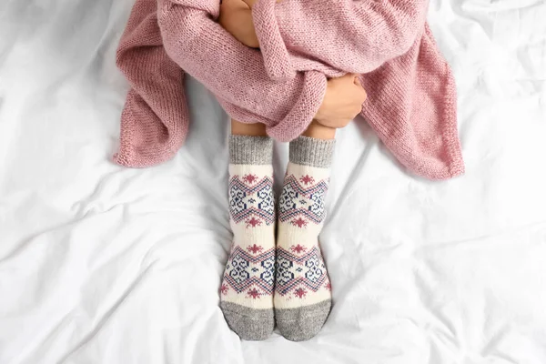 Woman wearing knitted socks on white fabric, top view. Warm clothes — ストック写真
