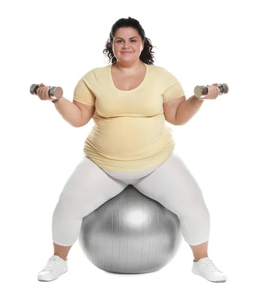 Избыточный вес женщина делает упражнения на пригодный мяч с гантелями на белом фоне — стоковое фото