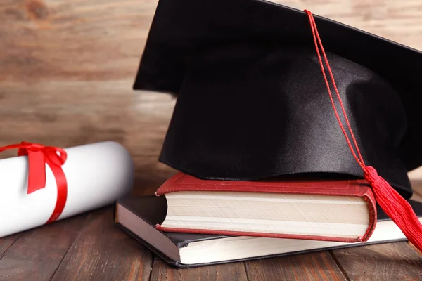 Afstudeerhoed, boeken en studentendiploma op houten tafel, close-up — Stockfoto